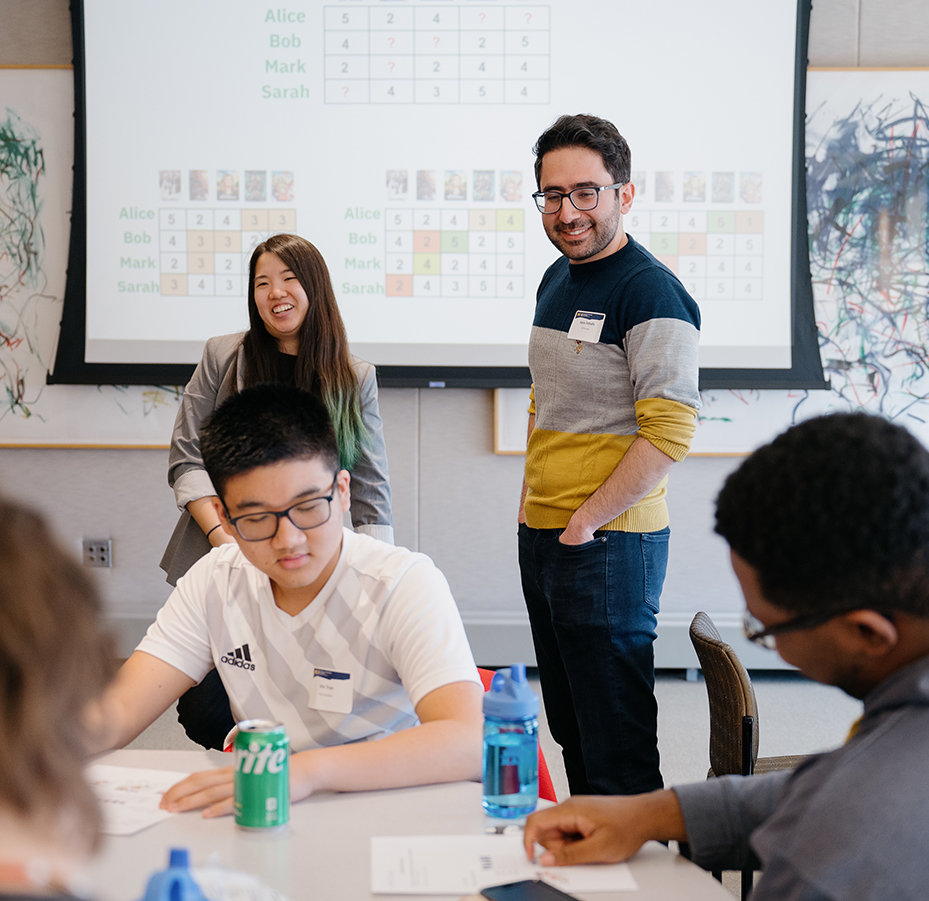 Two people help students with a math assignment