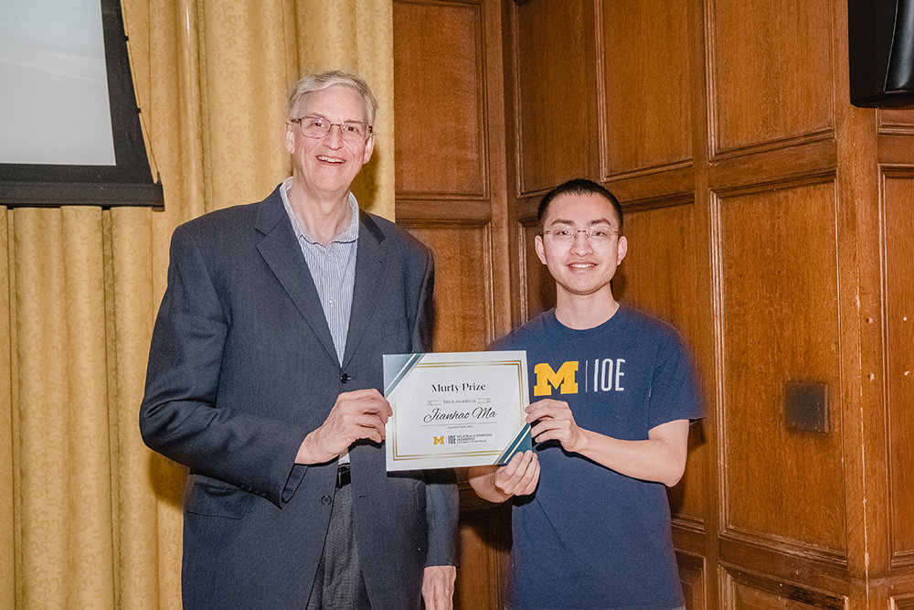 A man hands an award to a student