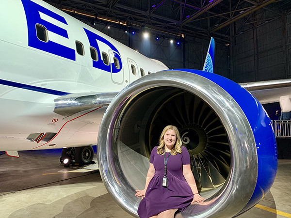 Kelsy Blake smiles and poses as she's sitting in an airplane engine