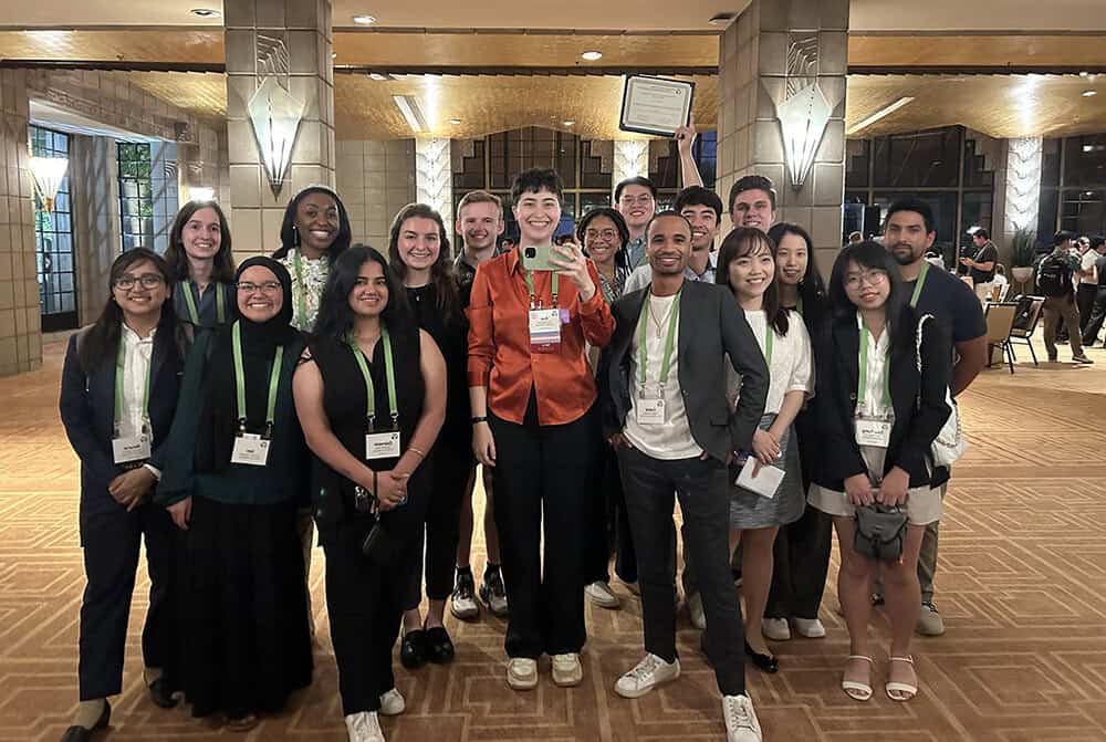 Large group of students in a conference center holding a certificate up