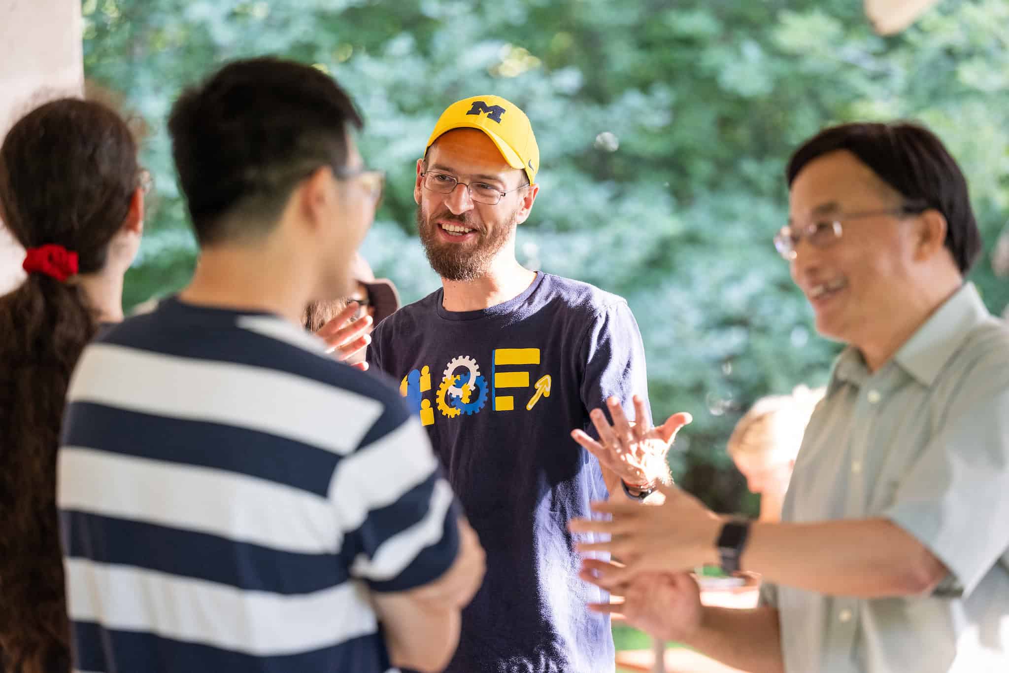 A man in yellow hat talking to a woman. Two people in front of them